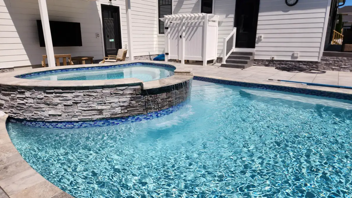 Custom inground pool installation with stone patio surround in Sussex County Delaware
