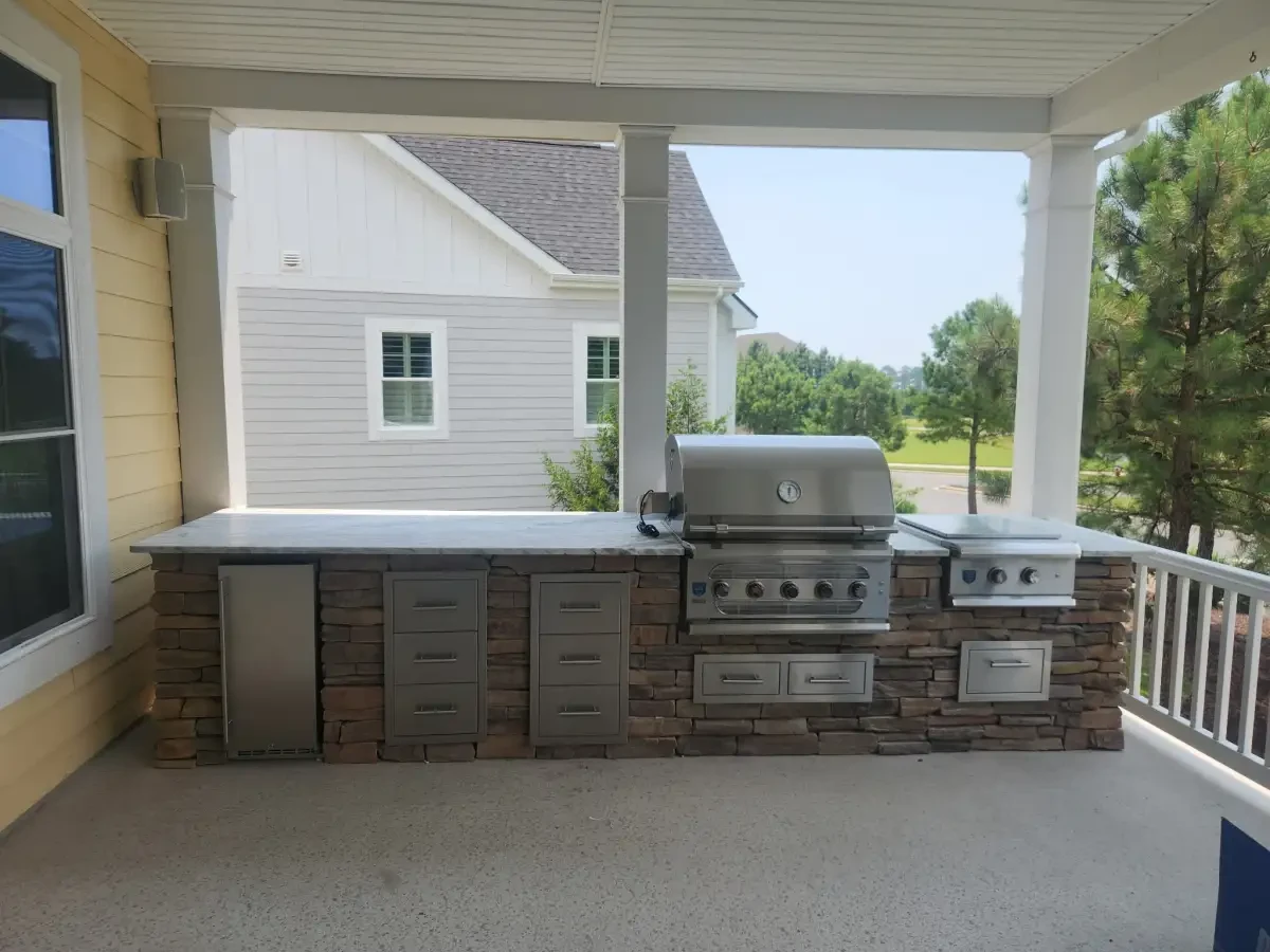 Built-in grill and stone kitchen island under a covered porch