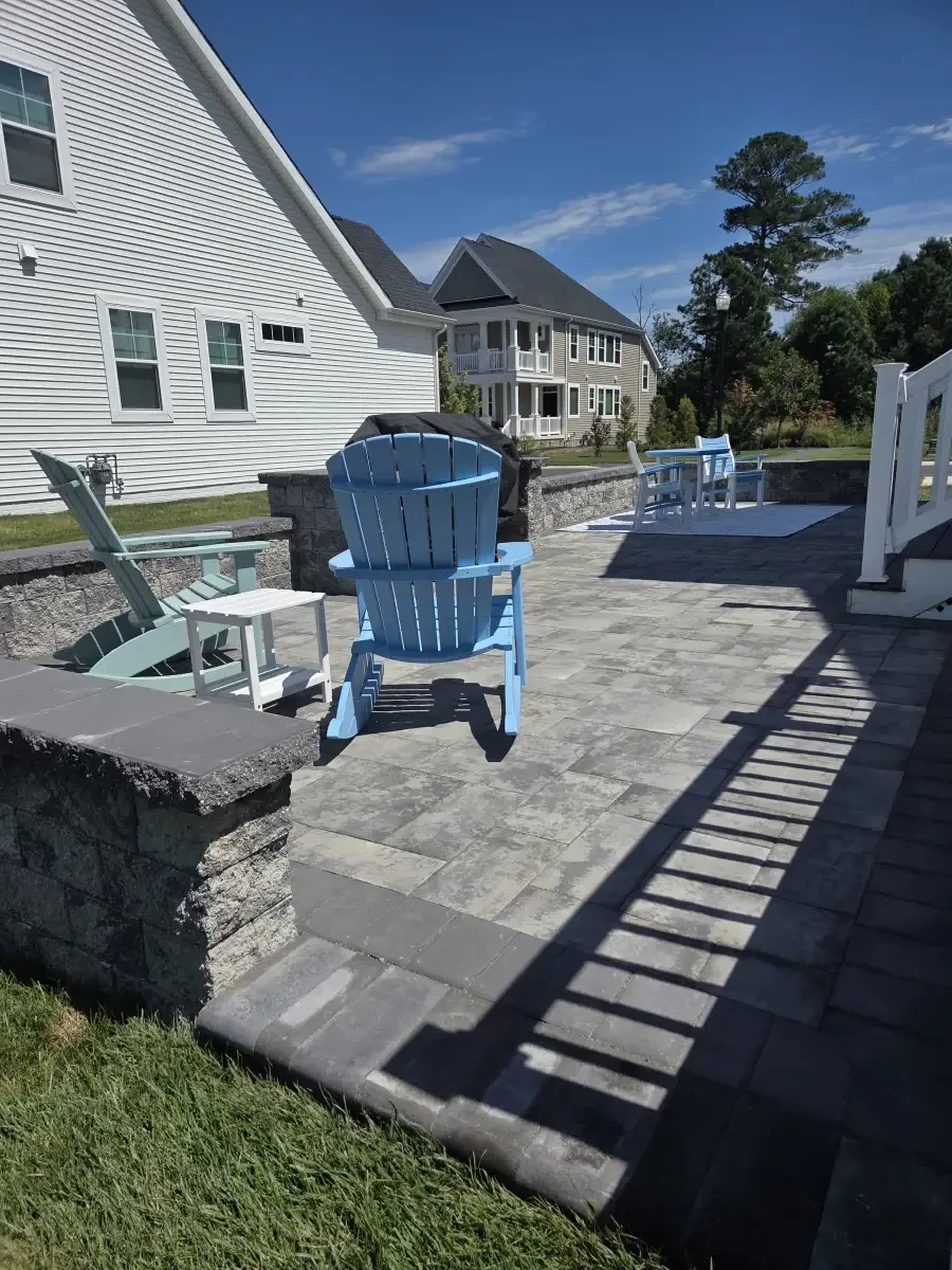Paver patio with blue chairs and a low seating wall