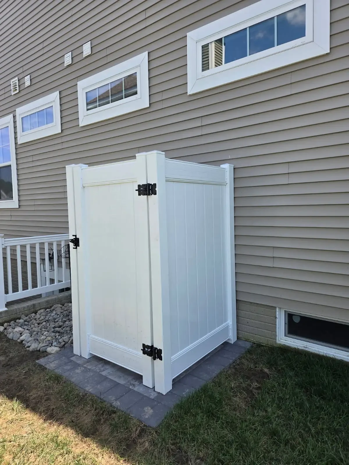 White outdoor enclosure with a privacy door beside a house
