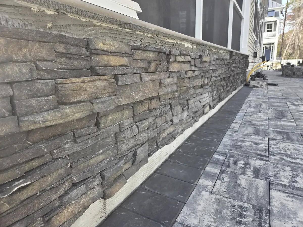 Stone wall and cap beside a paver patio