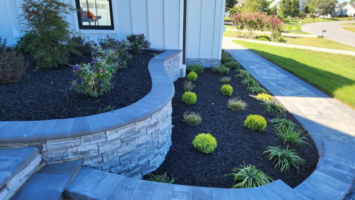 Curving stone garden wall beside a paver walkway